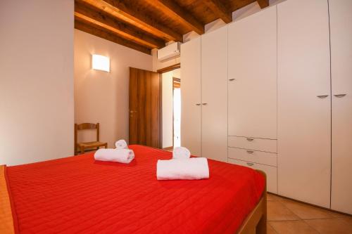 a bedroom with a red bed and white cabinets at Wohnung Mit Privatem Garten Und Schöner Aussicht in Moniga