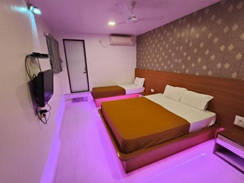 コールハープルにあるHotel Girija Residencyのベッド2台、テレビ、紫色の照明が備わる客室です。