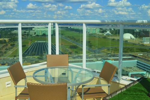 ブラジリアにあるFlat Brasília - Setor Hoteleiro Norteのガラスのテーブルと椅子、景色を望むバルコニー