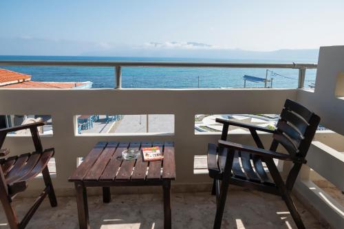 a table and chairs on a balcony with a view of the ocean at Argo Rooms-Papadakis in Kissamos