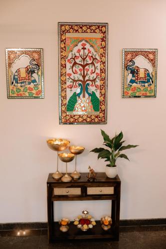 a table with a painting on the wall and two pictures at Adhyaya - Heritage Reverbed 4 BHK AC Triplex Villa in Vānivilāsa Puram