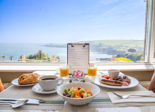 a table with breakfast food and a view of the ocean at Mevagissey Bay Hotel in Mevagissey