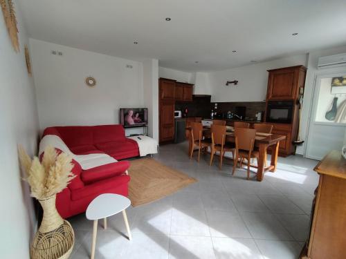un salon avec un canapé rouge et une cuisine dans l'établissement Gîte Ô fil du Tarn, à Lescure-dʼAlbigeois