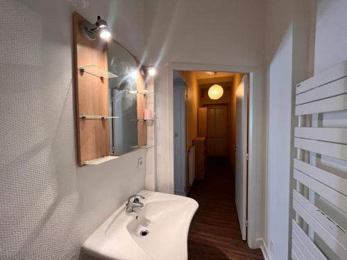 une salle de bain blanche avec un lavabo et un miroir dans l'établissement Studio PMR proche du centre, à Clermont-Ferrand