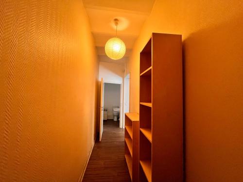 un couloir avec un mur orange et un luminaire dans l'établissement Studio PMR proche du centre, à Clermont-Ferrand