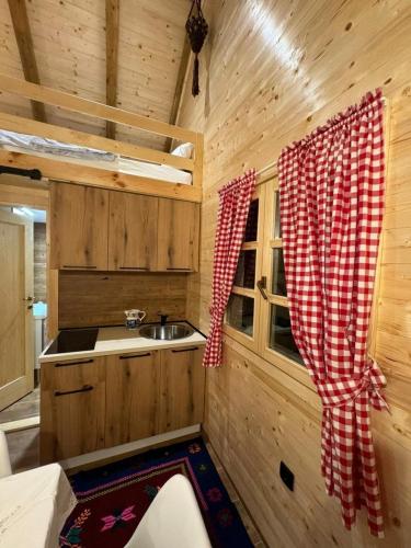 a kitchen with a sink and a red and white curtain at Etno house in Mojkovac