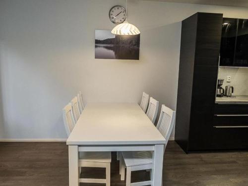 a white table and chairs with a clock on the wall at Modern Slope apartment 2 in Vuokatti