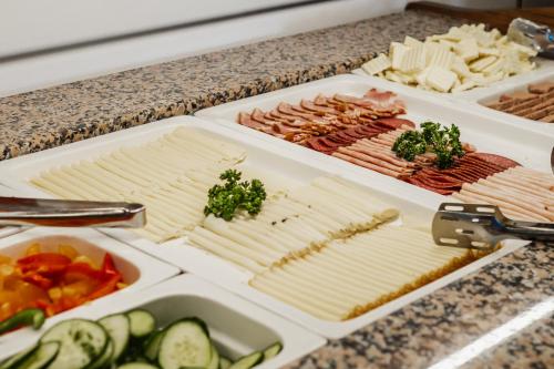 a buffet of cheese and meats and vegetables on a counter at Hotel Kristian in Kubova Huť