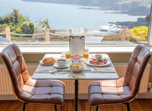 a table with food and a view of the ocean at Mevagissey Bay Hotel in Mevagissey