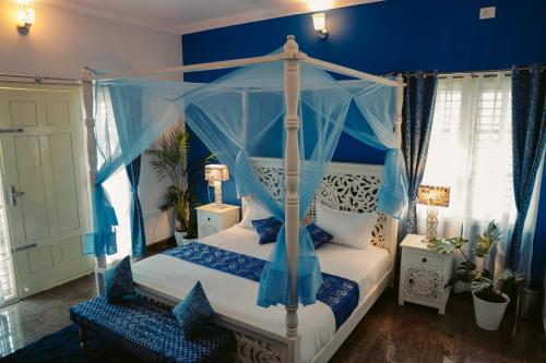 a bedroom with a canopy bed with blue walls at Adhyaya - Heritage Reverbed 4 BHK AC Triplex Villa in Vānivilāsa Puram