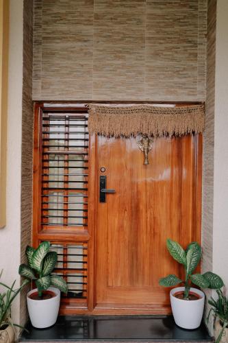 a wooden door with two potted plants in front of it at Adhyaya - Heritage Reverbed 4 BHK AC Triplex Villa in Vānivilāsa Puram