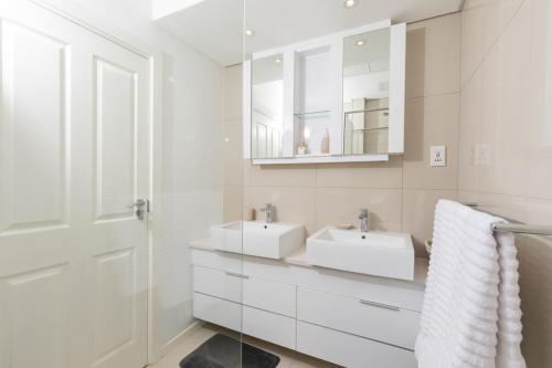 a white bathroom with two sinks and a mirror at iTowers Luxury Apartment in Gaborone