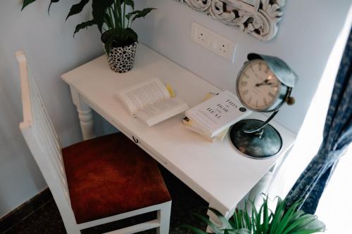 a white desk with a clock and books on it at Adhyaya - Heritage Reverbed 4 BHK AC Triplex Villa in Vānivilāsa Puram