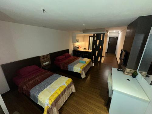 a hotel room with two beds and a desk at MFM Studio Kbcp in Kota Bharu