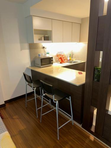 a kitchen with a counter with stools and a microwave at MFM Studio Kbcp in Kota Bharu