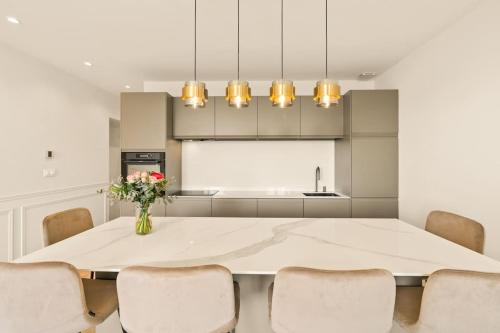 une cuisine avec une table blanche, des chaises et un vase de fleurs dans l'établissement Avenue Chic, à Cannes