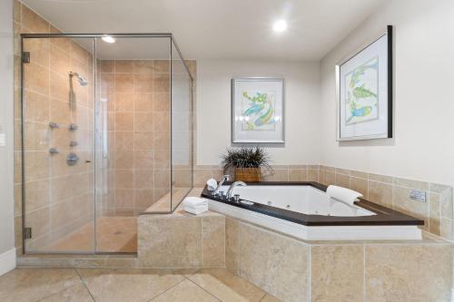 un baño con bañera y ducha de cristal en Turquoise D1703, en Orange Beach