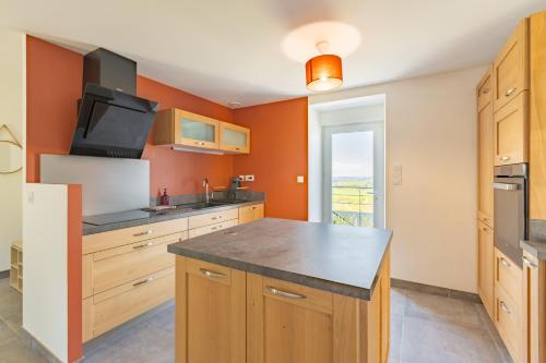 a kitchen with orange walls and a large kitchen island at Gîte de Lucie - Climatisé avec jardin de 800 m² in Lunac