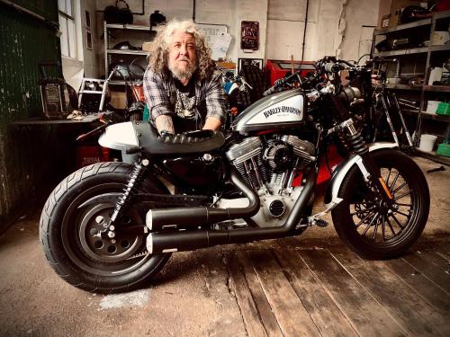 a man sitting on a motorcycle in a garage at Union Road Moto Velo Accommodation in Crediton