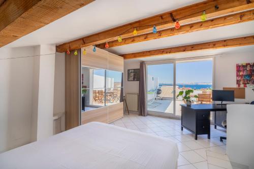une chambre avec un lit et un bureau et un balcon dans l'établissement Les Terrasses de Montredon - Magnifique vue mer, à Marseille