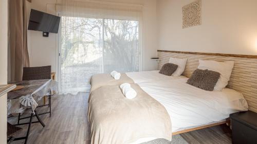 deux lits dans une chambre avec une fenêtre dans l'établissement Les Suites du Jardin 2 - La Chambre du Jour - 2 pers, à Chaumont