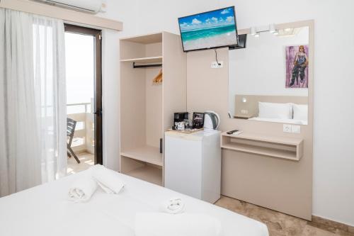 a white room with a bed and a tv on a wall at Argo Rooms-Papadakis in Kissamos