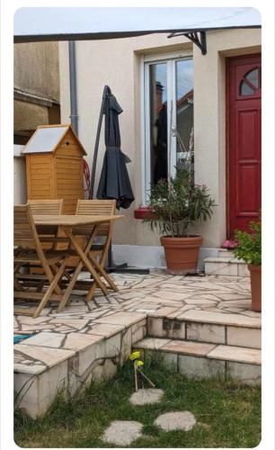 un patio avec une table et un parasol à côté d'une porte dans l'établissement Chez Lucile, à Villeneuve-le-Roi