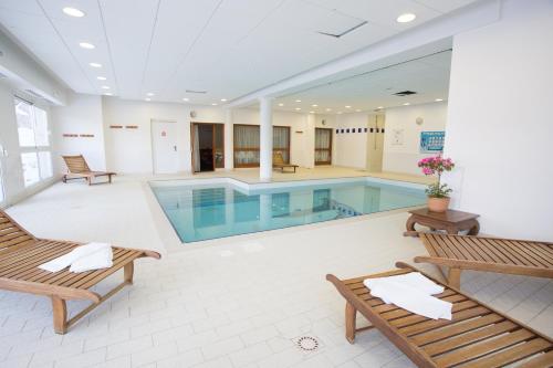 a swimming pool in a building with benches and chairs at Les Gentianes by Actisource in Puy-Saint-Vincent