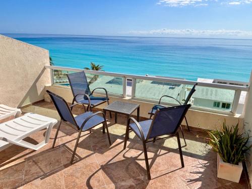 a balcony with chairs and a table and the ocean at Brisas Shores Penthouse Beachfront, Ocean View Terrace Cancun Hotel Zone, 2 bedrooms in Cancún
