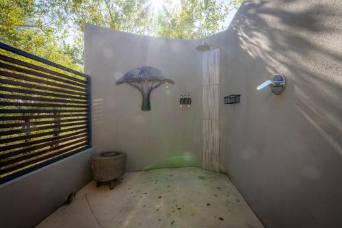 a small room with a shower with a umbrella on the wall at Rafiki Bush Lodge in Hoedspruit
