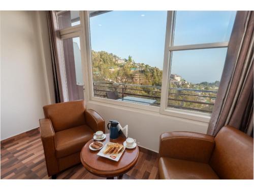 a room with a table and a chair and a window at Hotel Shiva Sanctuary by DLS Hotels, McLeod Ganj in Dharamshala