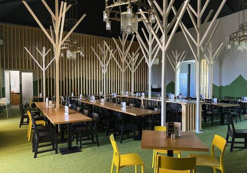 a dining room with wooden tables and yellow chairs at Horská ubytovňa Hrebienok in Smokovce