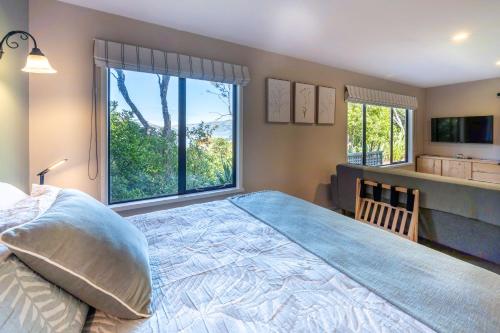 ein Schlafzimmer mit einem großen Bett und einem großen Fenster in der Unterkunft Laneside - Akaroa Holiday Cottage in Akaroa