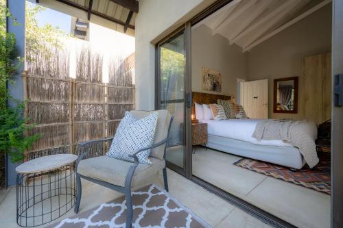 a bedroom with a bed and a chair on a balcony at Rafiki Bush Lodge in Hoedspruit