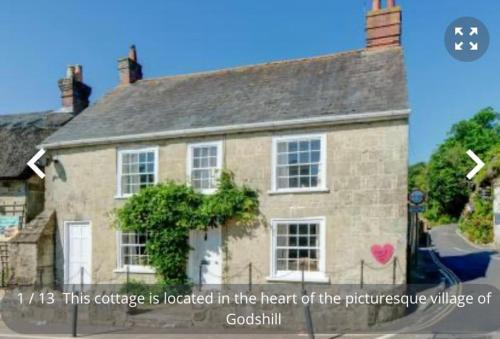 a house with a sign that reads this cottage is located in the heart at Christmas Cottage, Isle of Wight in Godshill