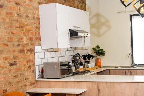 Una cocina con gabinetes blancos y un microondas. en Palm Nest, en Kempton Park