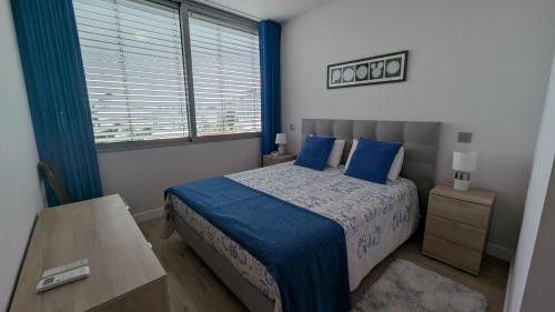 een slaapkamer met een bed met blauwe lakens en een raam bij Sol do Til Apartment in Funchal