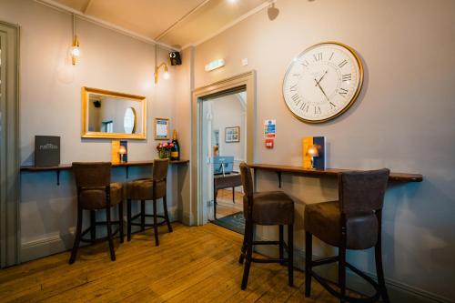 a bar with stools and a clock on the wall at Purchases Restaurant & Accommodation in Chichester