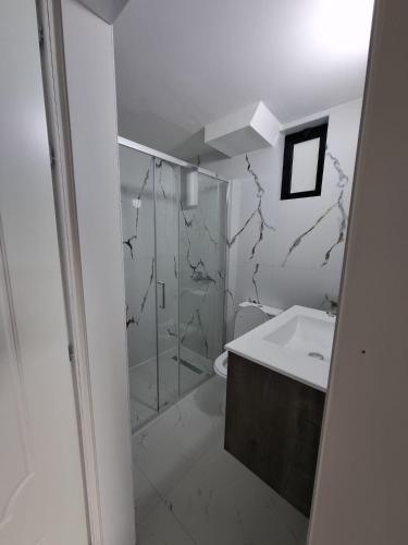a white bathroom with a shower and a sink at Koman Paradise by Romina in Shkodër