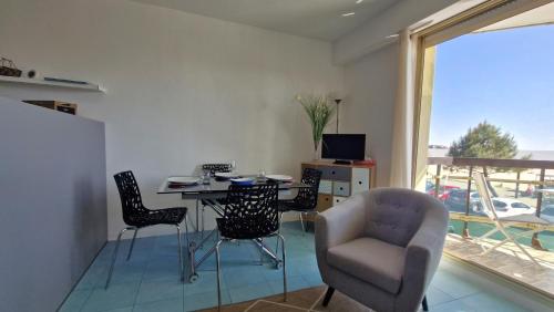 un salon avec une table et des chaises et une fenêtre dans l'établissement Saint Georges de Didonne - PLEINE VUE MER pour ce STUDIO CABINE face à la plage, à Saint-Georges-de-Didonne