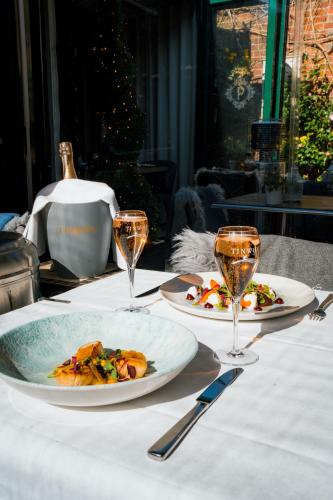 a table with two plates of food and wine glasses at Purchases Restaurant & Accommodation in Chichester