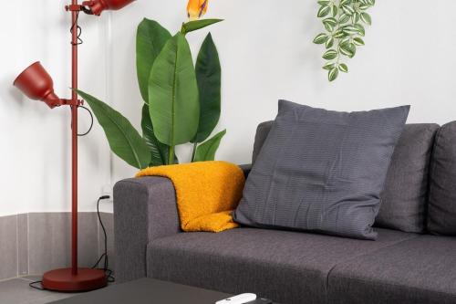 Un sofá gris con una almohada amarilla y una planta. en Luxe - Cozy - Seas of Copenhagen, en Copenhague