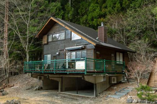 a house with a balcony on the side of it at Lake England 富士山が見える隠れ家ロッジ in Fujikawaguchiko