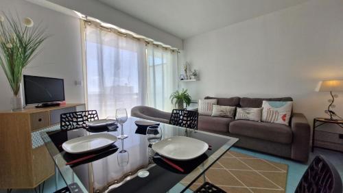 - un salon avec un canapé et une table avec des verres à vin dans l'établissement Saint Georges de Didonne - PLEINE VUE MER pour ce STUDIO CABINE face à la plage, à Saint-Georges-de-Didonne