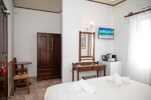 a bedroom with a bed with white sheets and a mirror at Argo Rooms-Papadakis in Kissamos