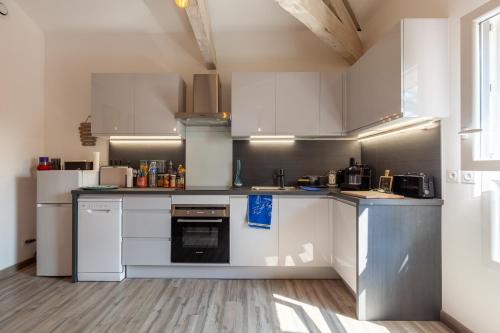 a large kitchen with white cabinets and appliances at Appartement Lumineux refait à Neuf in Sanary-sur-Mer