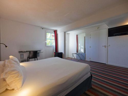 a bedroom with a large white bed and a desk at Hotel Donibane Saint-Jean-de-Luz in Saint-Jean-de-Luz