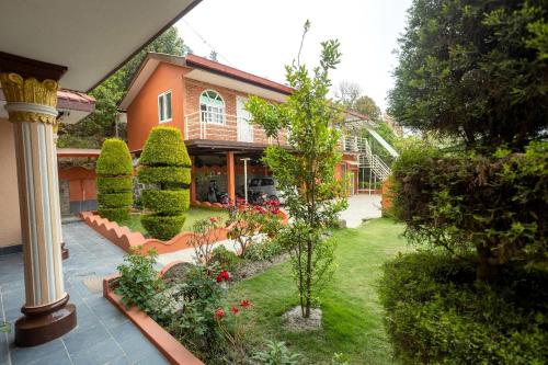 a garden in front of a house with bushes and trees at Kathmandu room with great view, like resort in Bālāju