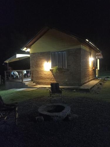 a chair in front of a house at night at Vale Infinito Chalé in Córrego do Bom Jesus