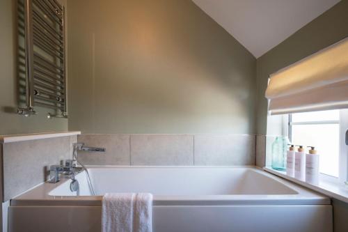 een badkamer met een bad en een raam bij Stable Cottage, Friston in Friston